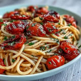 A luscious bowl of cherry tomato confit pasta with fragrant garlic oil and fresh basil.