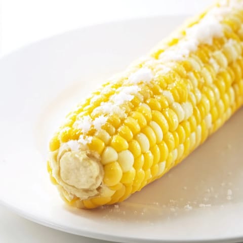 Golden-grilled corn on the cob, its sweet kernels visible, ready to be enjoyed as a summer meal.