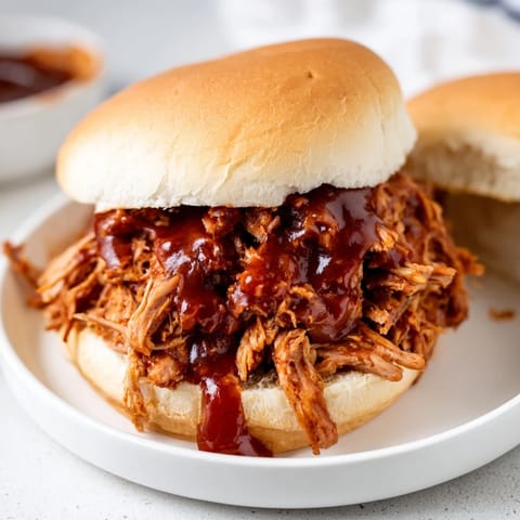Savory Pulled Pork Sandwich, showing tender meat overflowing, nestled inside a fluffy, split-top bun, ready to eat.
