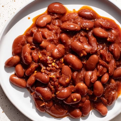 Steaming bowl of baked beans, rich tomato sauce coats tender beans, perfect comfort food.