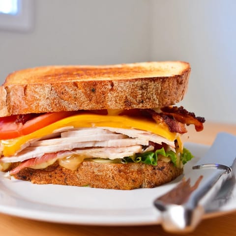 This hearty Turkey Club Grilled Cheese shows melted cheese oozing from a golden, crispy sourdough crust over fresh lettuce and bacon.