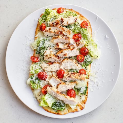 Two slices of Caesar Chicken Flatbread served with lemon wedges, showcasing fresh romaine and melted Parmesan on naan.  