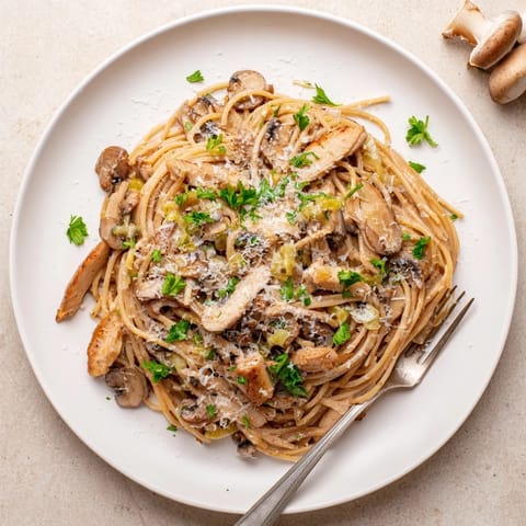A comforting bowl of Creamy Mushroom Chicken Spaghettini, featuring golden-brown mushrooms and savory chicken nestled in a light, silky cream sauce.  