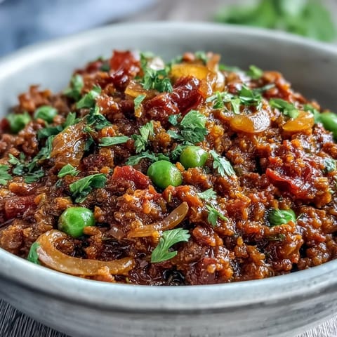 Steaming bowl of Venison Keema Curry, rich with peas and aromatic spices, served over fluffy basmati rice.