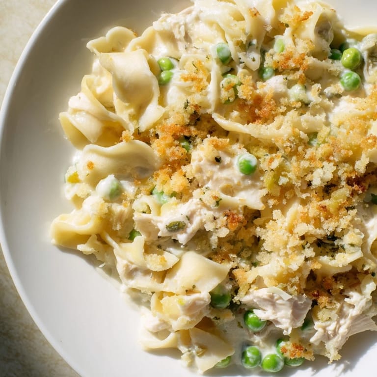 Steaming hot Tuna Casserole with a crispy breadcrumb topping, peas, and creamy sauce; a delicious main dish.