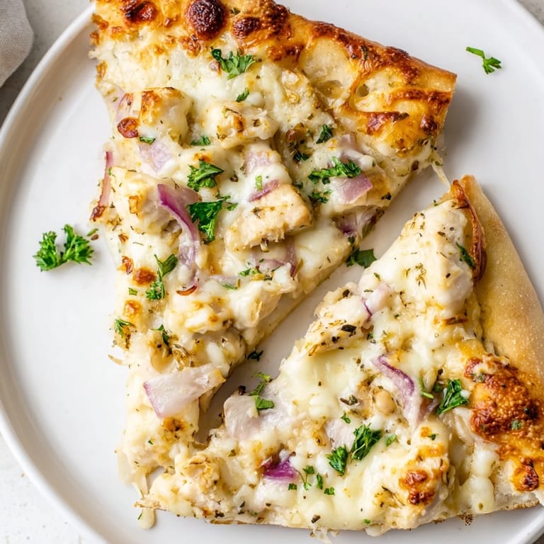 Hot Chicken Alfredo Pizza served on a platter, garnished with fresh parsley, ready to be enjoyed as a comforting Italian-American main dish.