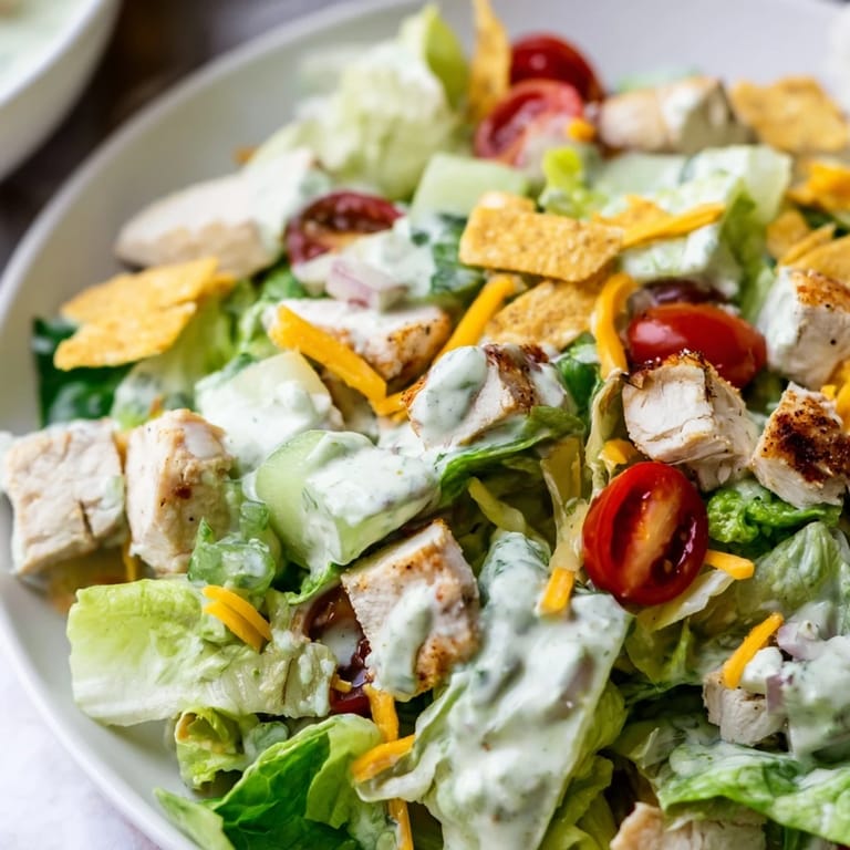 Bright green romaine salad loaded with spicy jalapeño ranch chicken, sharp cheddar, and crunchy tortilla strips for garnish.