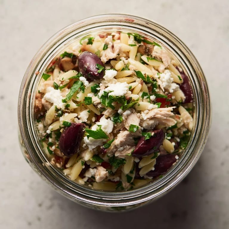 A meal-prep Greek Pasta Chicken Salad Jar with orzo, chicken, and veggies is ready for grab-and-go lunches.