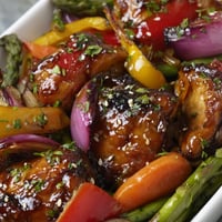 Tender chicken pieces and bright bell peppers glazed in honey garlic sauce, roasted on a sheet pan with asparagus and snap peas.
