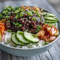 Korean Beef Bowl served over fluffy white rice, topped with spicy beef, crisp cucumber, and tangy kimchi.