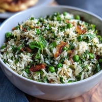 A bowl of fragrant Spring Pea and Mint Rice Pilaf, showcasing vibrant green peas and fresh mint leaves.