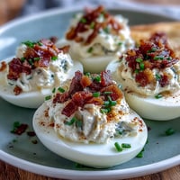 Crispy bacon and creamy ranch deviled eggs, garnished with chives and paprika for a savory appetizer.